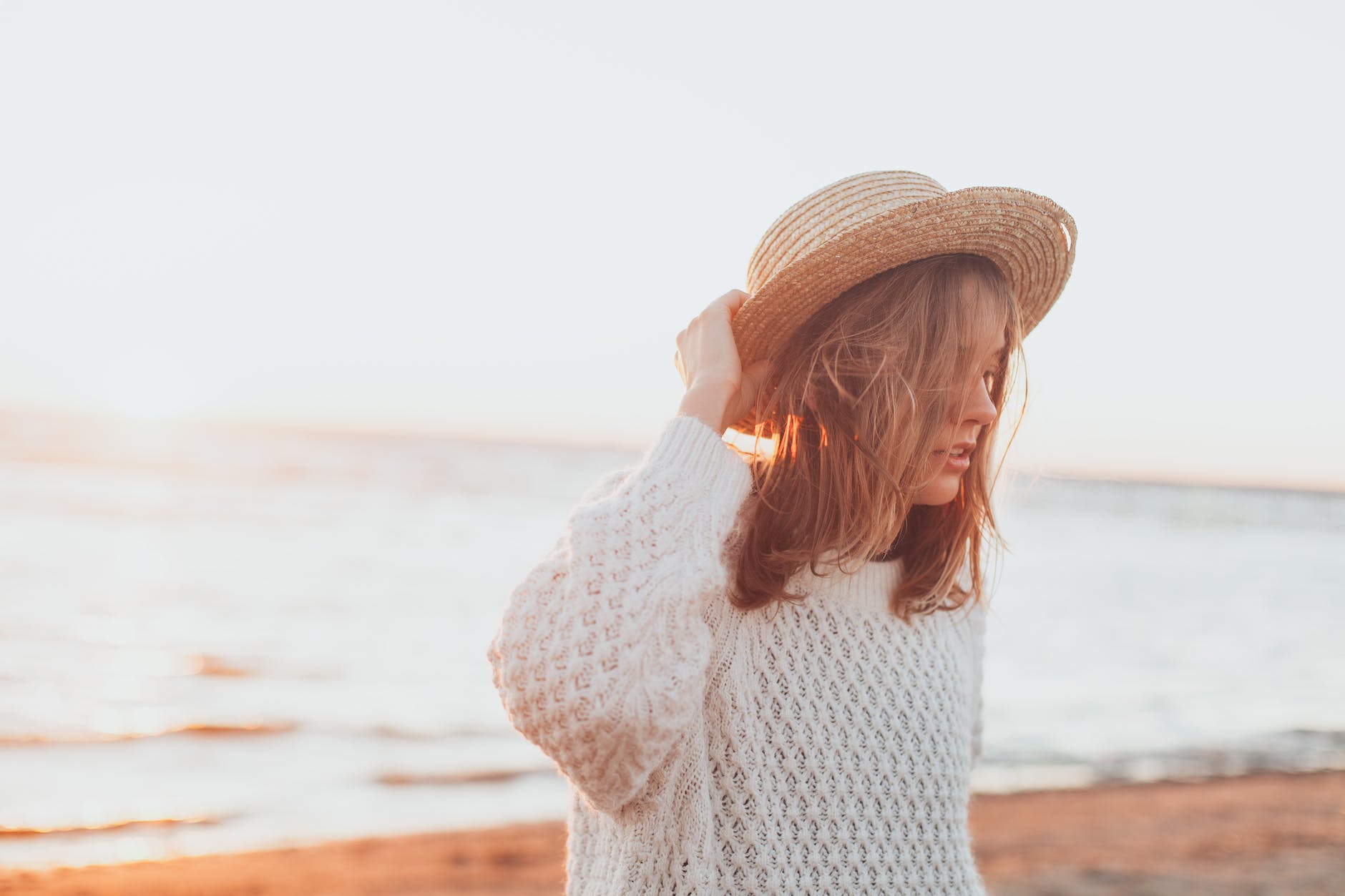 selective focus photography of woman holding brown straw hat