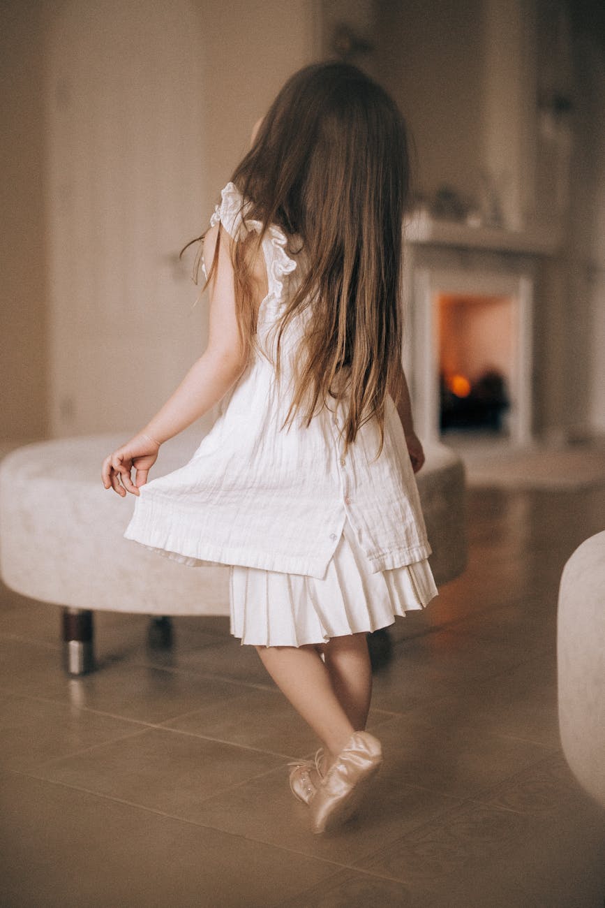 back view of little girl in dress and ballet shoes